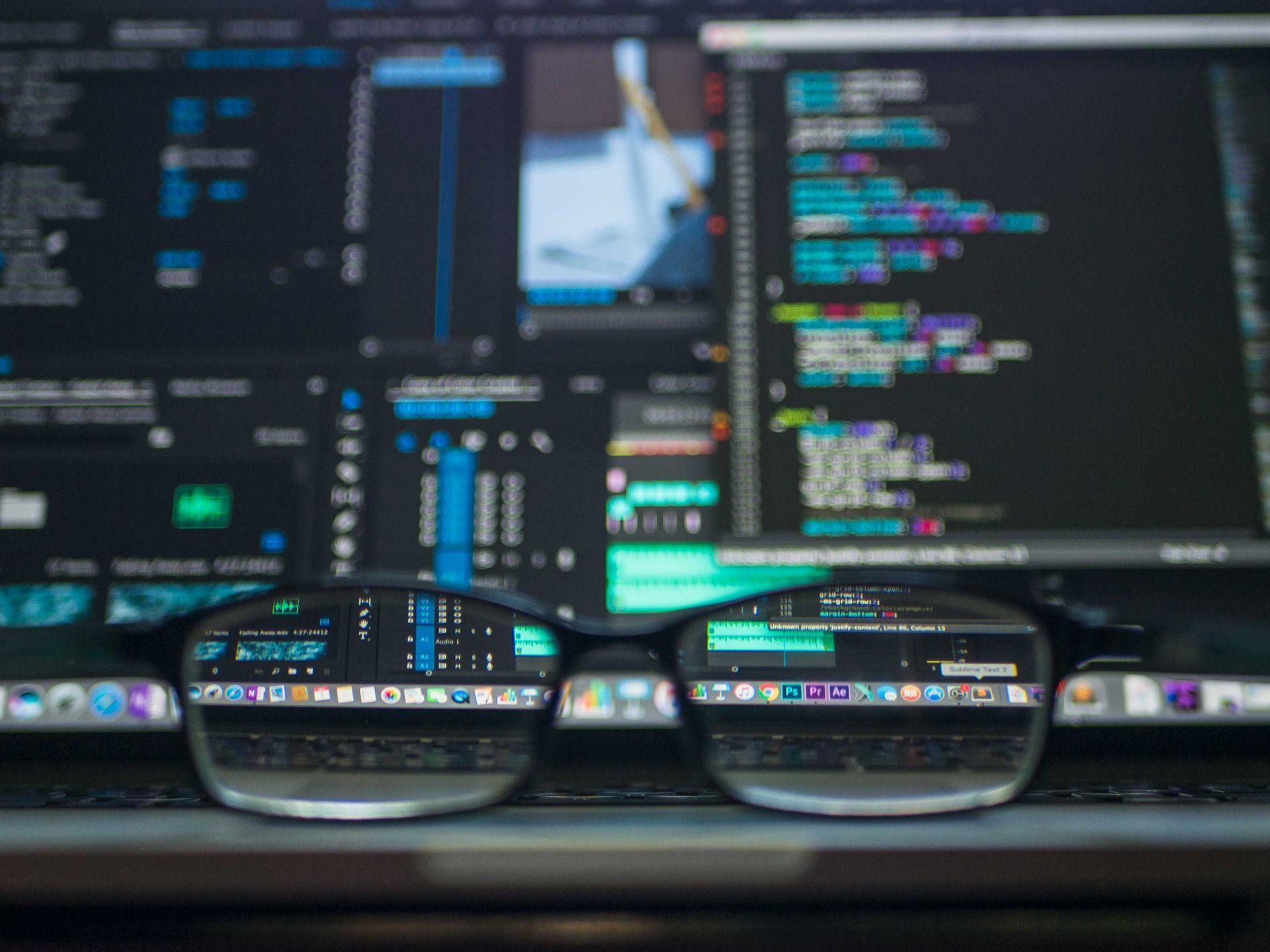 Laptop open on a wooden desk showing source code